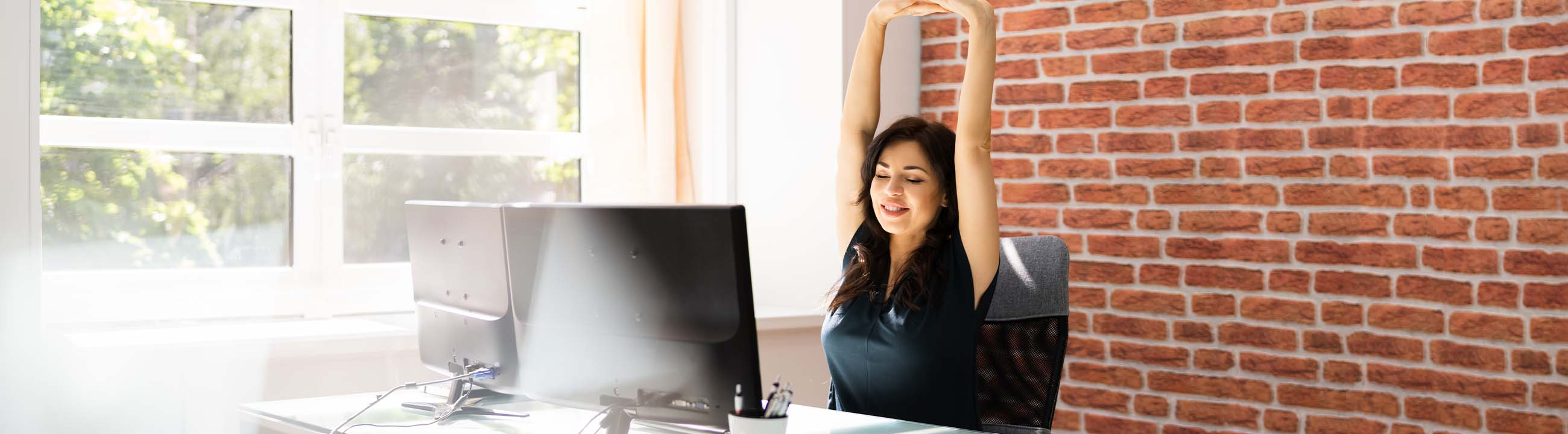 Mujer sentada en la oficina estirando los brazos