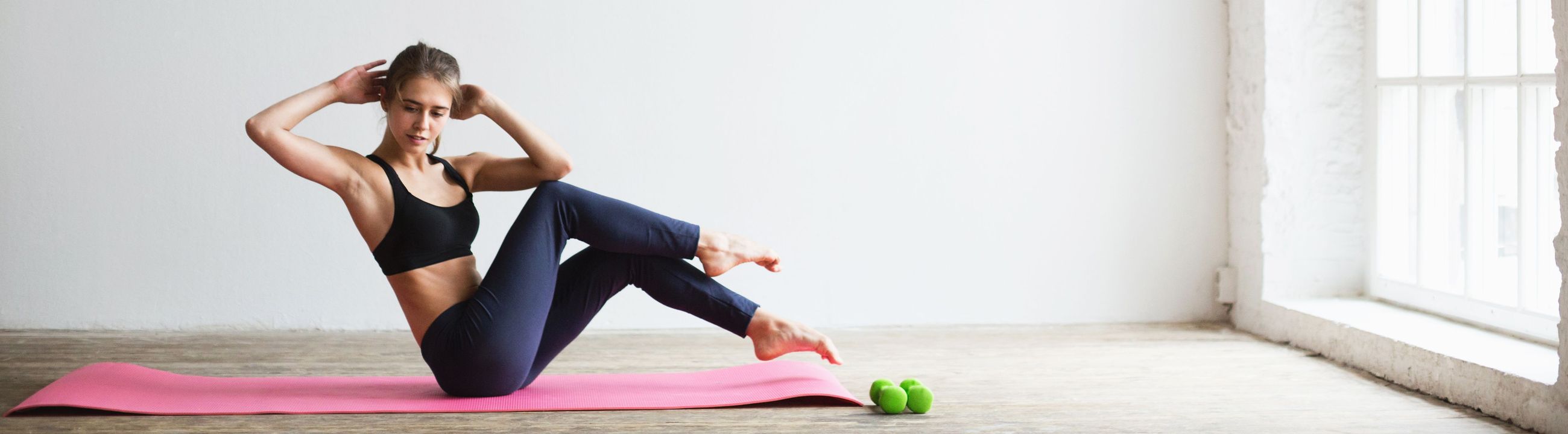 Mujer atlética haciendo sit-ups butterfly sobre una esterilla de yoga